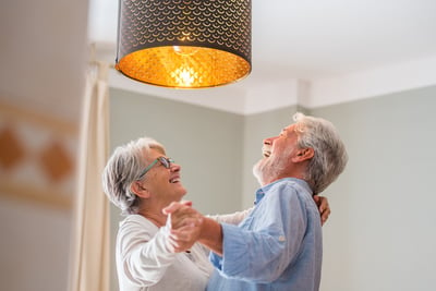 alegre-pareja-senior-bailando-riendo-casa-feliz-pareja-ancianos-celebrando-bailando-sala-estar-pareja-ancianos-divirtiendose-tomados-mano-disfrutando-bailando-juntos-casa