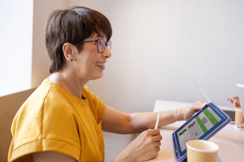 elderly-woman-working-tablet-drinking-coffee