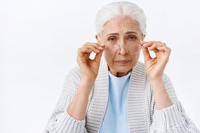 old-cute-senior-woman-in-retirement-house-with-grey-combed-hair-squinting-cant-read-small-letters-bend-forward-touching-glasses-as-trying-focus-on-word-to-read-it