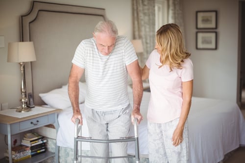 senior-woman-helping-man-walk-with-walker