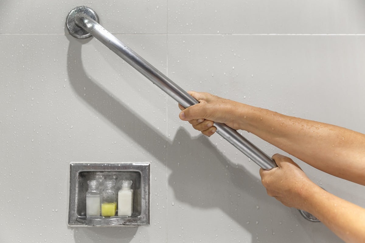 senior-woman-holding-on-handrail-for-safety-in-bathroom