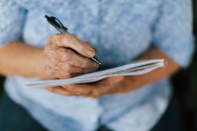 senior-woman-writing-down-her-memories-into-notebook